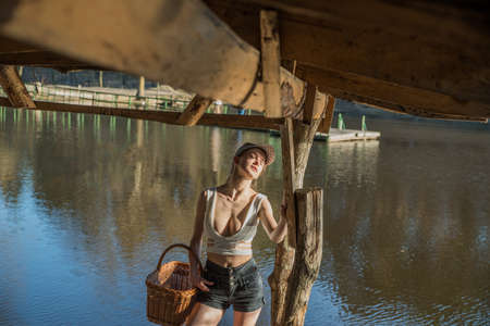 A girl with a basket in a wooden building on the lake in the warm evening light of the setting sun.の写真素材
