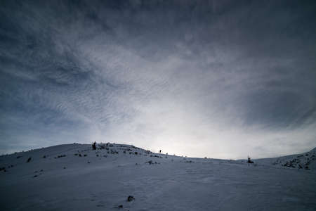 Winter mountains with snow under a dark winter sky.