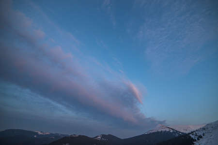 Winter mountains with snow under a dark winter sky.