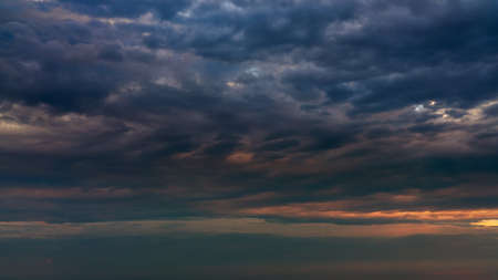 Sun beams or rays breaking through the dark clouds at sunset. Beautiful spectacular conceptual meditation background. Artistic golden sunset edit.の写真素材