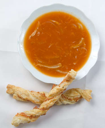 Yellow soup in a white plate with bread.