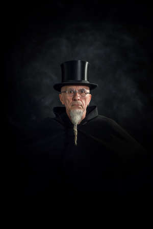 Portrait of a mysterious male magician in a black high top hat and black robe.の写真素材