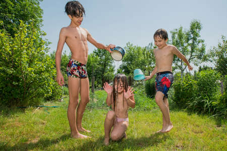 Children pour water on each other on a hot sunny summer day.