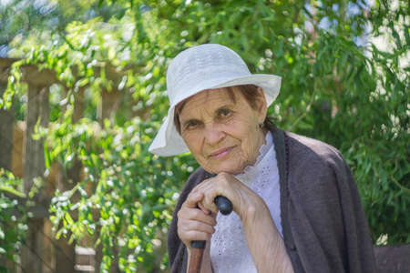 Portrait of an elderly woman in a white panama against a background of green foliage.の写真素材