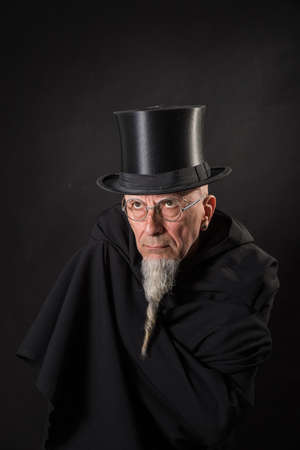 Portrait of a mysterious male magician in a black high top hat and black robe.の写真素材