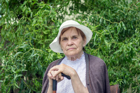 Portrait of an elderly woman in a white panama against a background of green foliage.の写真素材