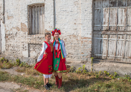 Kiliya. Odessa region. Ukraine. September 12, 2021: Girls in bright multi-colored Ukrainian and Bulgarian folk clothes against the background of an old brick wall.のeditorial素材