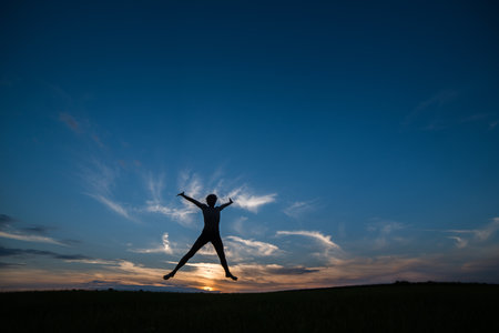 Jump of a man against the background of the evening sunset sky. silhouette.の写真素材