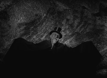 Portrait of a mysterious male magician in a black high top hat and black robe.の写真素材