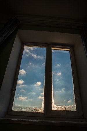 Blue sky with clouds in the frame of a misted window.の写真素材