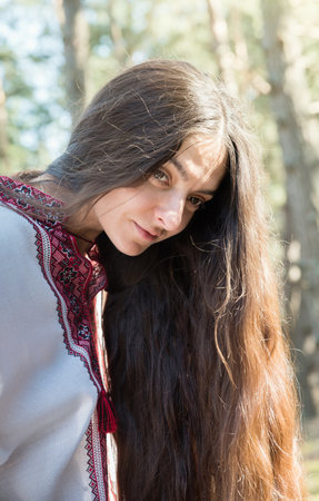 Long-haired Ukrainian girl in an embroidered national shirt in the forestの写真素材