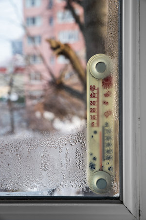 Thermometer behind a window wet with condensation. Selective focus.の写真素材