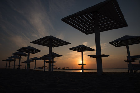 Silhouettes of wooden beach umbrellas at sunset on the sea beach.の写真素材