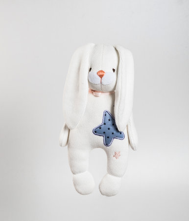 Soft toy rabbit with ears down and a star on his chest. Isolated on a white background.の写真素材
