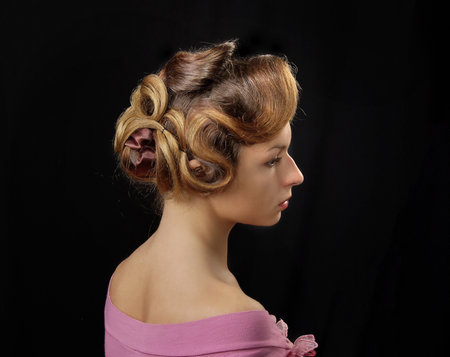 Portrait of a woman on a black background with a retro hairstyle. Beautiful woman. Photo in vintage style.の写真素材