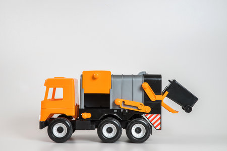Multi-colored plastic children's toy cars on a white background. Orange garbage truck.の写真素材