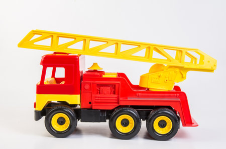 Multi-colored plastic toy trucks for children's games on a white background. Red fire truck with telescopic antenna.の写真素材