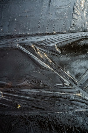 Freezing. Beautiful ice on a puddle with orange dry leaves, top viewの写真素材