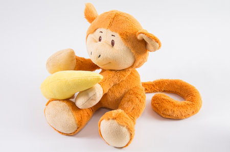 Plush children's toy monkey with banana on a white background.の写真素材