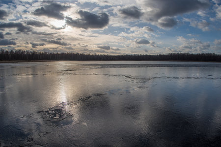 Spring lake covered with thin transparent cracking ice.の写真素材