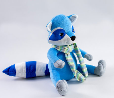 Plush blue toy raccoon with a striped tail on a white background.の写真素材
