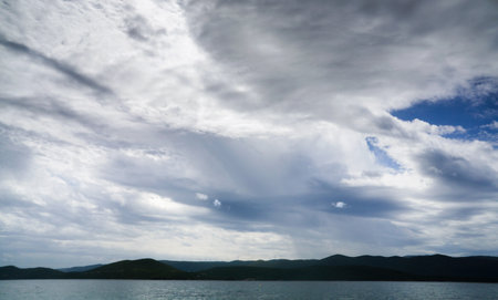 Cloudy sky over the sea and the silhouette of the mountains.の写真素材