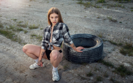Young athletic woman near a car tire in the evening lightの写真素材