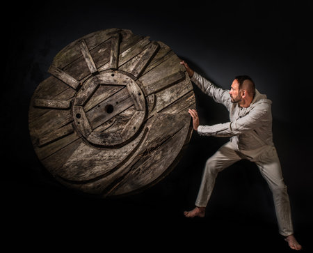 A man tries to stop a wheel rolling towards him. Motion blur.の写真素材