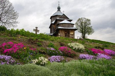 An old wooden Ukrainian Orthodox church with colorful flower beds.の写真素材