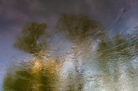 Multicolored reflections of trees in water. Abstract texture of water.の写真素材