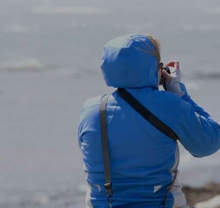 woman taking picture of oceanの写真素材