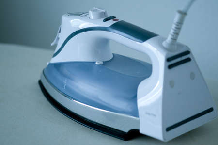 iron laying flat on an ironing board cord upの写真素材