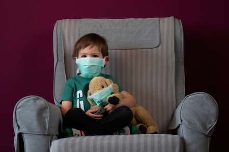 Coronavirus, Covid-19, Boy and his stuffed puppy in protection masks, quarantine at homeの写真素材