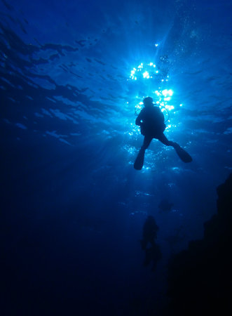 Silhouette of scuba diver in deep blue sea with sun rays, Diver in blue, near St. Johns in Red Sea, Egypt, underwater photographyの写真素材