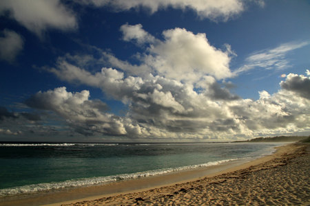 Tropical beach under the blue sky with white clouds and sun raysの写真素材