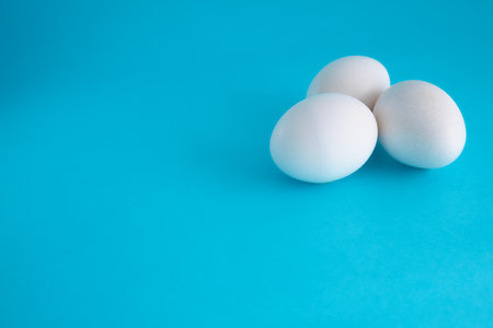 Three white eggs on a blue background. close-up. copyspace.の写真素材