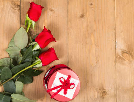 Red roses with present on wood backgroundの写真素材