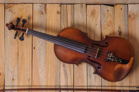 one violin image .old brown stringed wooden instrument isolated on the wood background and bowの写真素材
