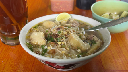 Thai noodle soup with pork in a bowl on wooden tableの写真素材