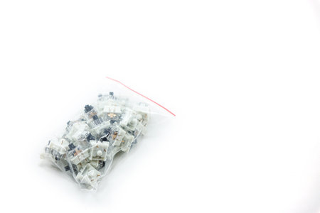 a collection of black mechanical keyboard switch keys wrapped in plastic isolated on white backgroundの写真素材