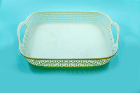 white plastic basket with woven pattern isolated on a turquoise background.の写真素材
