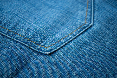 Blue jeans fabric background texture with stitching details. Close-up view.