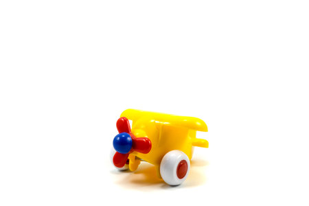 Yellow paint plastic toy airplane with red propeller isolated on white backgroundの写真素材