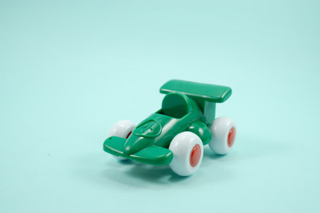 Green paint plastic toy racing car with number one isolated on turquoise background.の写真素材