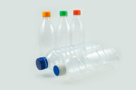Close-up of used plastic bottles for recycling with colorful bottle caps isolated on a white background.の写真素材