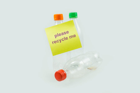 close-up of used plastic bottles for recycling with sticky notes please recycle me isolated on a...