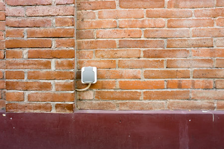 the power outlet is in a city park with red brick walls.