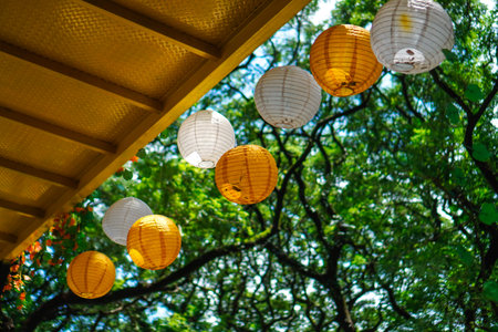 Lanterns are hung under the bridge with a background of sky and green trees.の写真素材