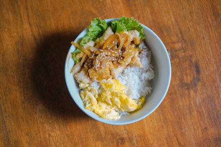 Chicken karage rice and teriyaki sauce sprinkled with sesame seeds on a wooden table background.の写真素材