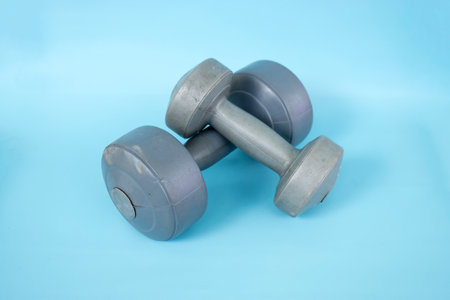 Two silver plastic dumbbells isolated on a blue background.の写真素材